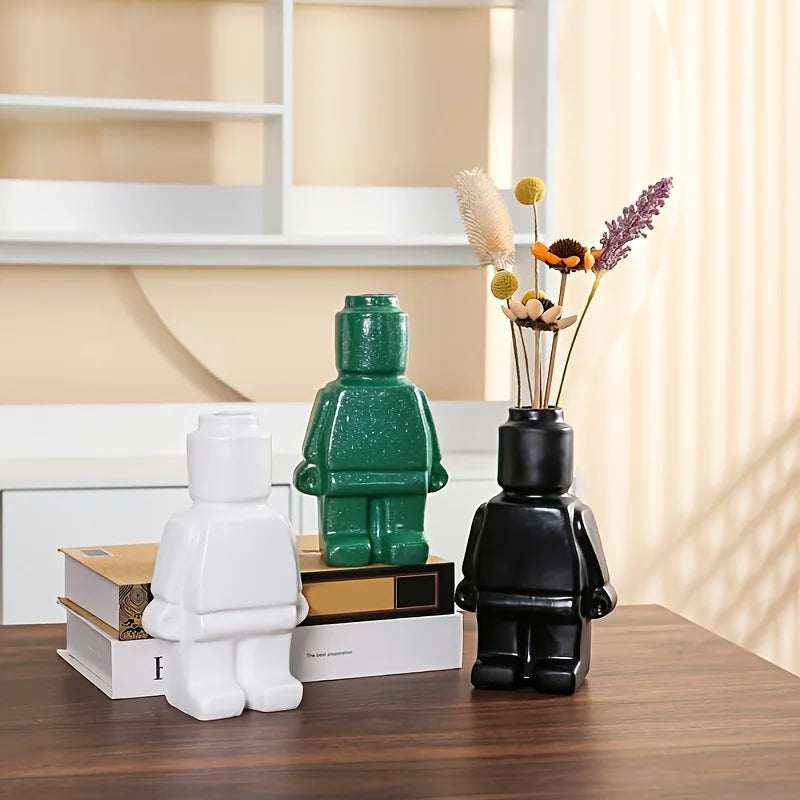 Trois vases Figura en céramique mate, blanc, vert moucheté et noir, posés sur des livres
