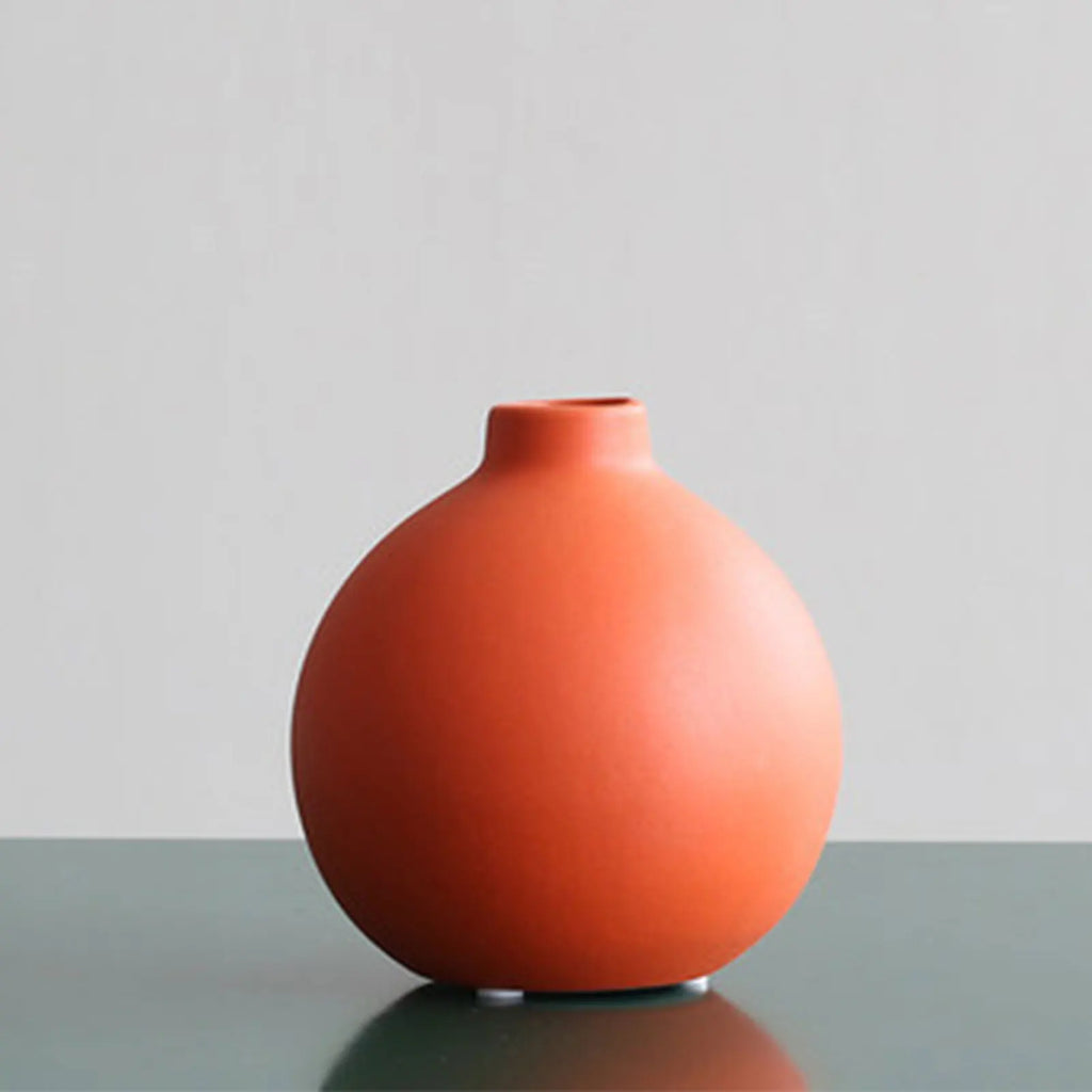 Vase Sienne boule terracotta posé sur une surface claire