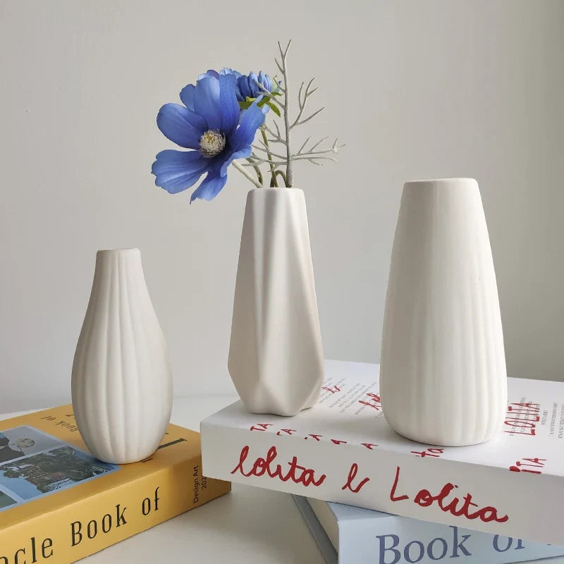 Vase cannelé blanc avec une fleur, posé sur des livres