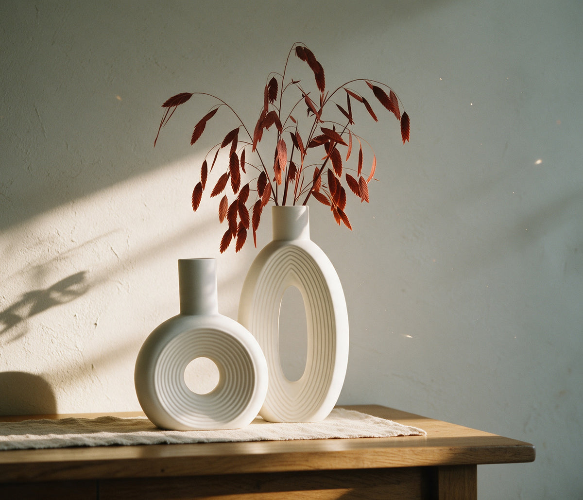 Vases Arche disque spiralé et anneau cannelé sur une console en chêne, lumière d'automne